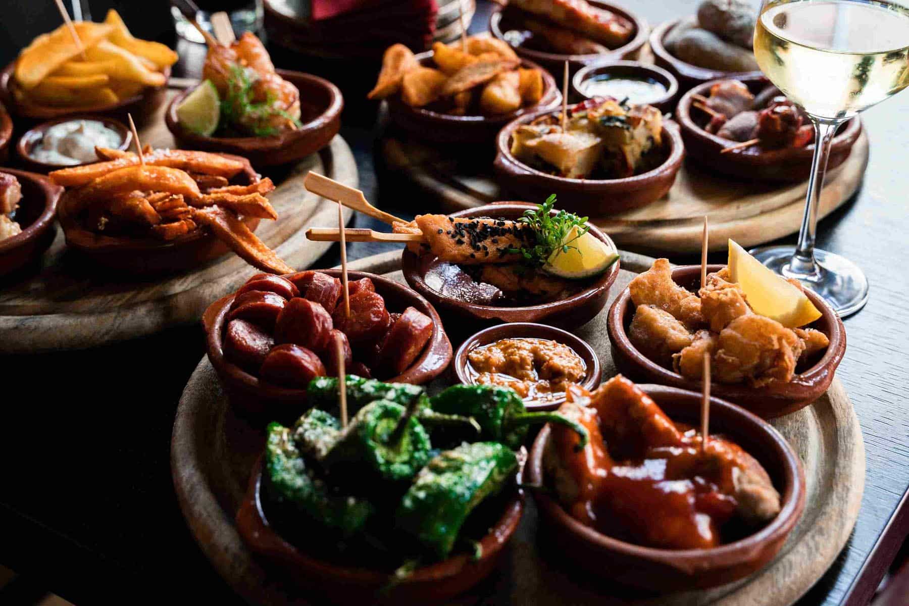 Spansk tapasbord med småretter, aioli og vin i stemningsfull belysning